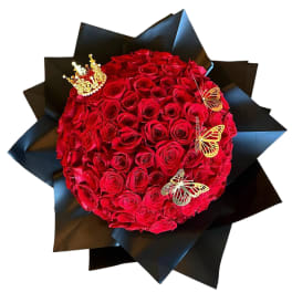 Round bouquet of red roses wrapped in black paper with butterfly accents