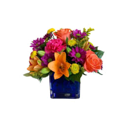 Colorful bouquet in a blue glass vase with roses, lilies, and daisies