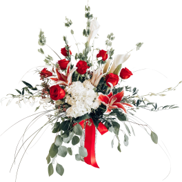Red roses and white lilies in a tall vase with a red ribbon