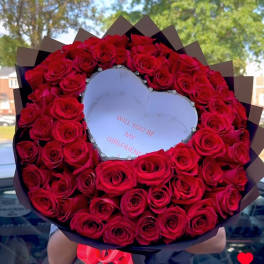 Heart-shaped bouquet of red roses with a note in the center
