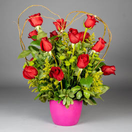 Red roses in a pink pot with a decorative twig arch