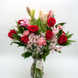 Bouquet of red roses, pink lilies, and carnations in a glass vase