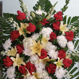 Large standing floral spray with red roses, white blooms, and yellow lilies