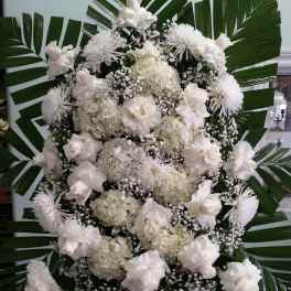 White floral standing spray with large palm leaves