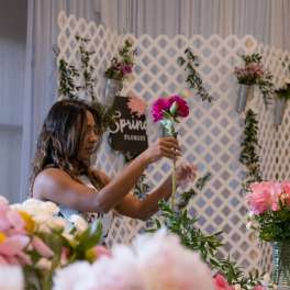 Woman arranging a pink flower on a lattice floral display