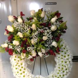 Large funeral wreath of white daisies and red and cream roses on an easel