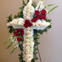 Cross-shaped floral arrangement with red and white roses on a stand