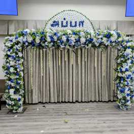 Large floral arch with white and blue flowers around a curtain backdrop