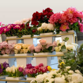Tiered display of assorted bouquets in white boxes with pink, red, white, and purple flowers