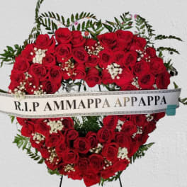 Heart-shaped red rose funeral wreath with a memorial ribbon