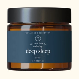 Amber jar of deep sleep salve with a black lid and blue label