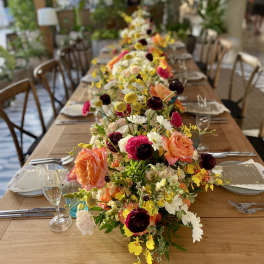 Long table with colorful floral centerpieces and place settings