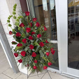 Tall standing arrangement of red roses with greenery on a metal easel