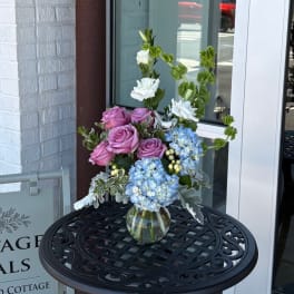 Pink roses and blue hydrangeas in a glass vase with white blooms