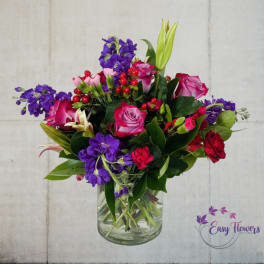 Bouquet of pink and red roses with purple flowers in a glass vase