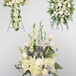 White funeral floral tributes with a cross, wreath, and urn arrangement