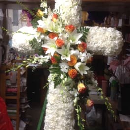 Large white floral cross with orange roses and lilies