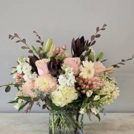 Pink roses and white blooms arranged in a square glass vase