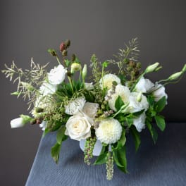 White roses and mums arranged in a low white vase.