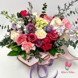 Mixed bouquet of roses, carnations, and purple accent flowers with ribbon wrap