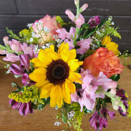 Mixed bouquet with a sunflower, peach roses, and pink blooms