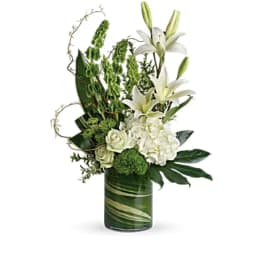 White lilies and roses arranged in a green glass vase