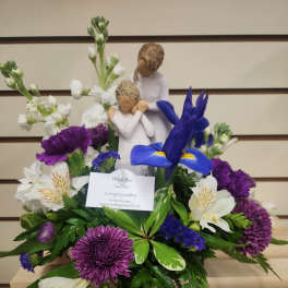 Purple and white floral arrangement with a mother-and-child figurine