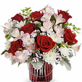 Red roses and pale pink flowers in a red glass vase