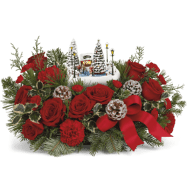 Red roses arranged with a small winter village centerpiece
