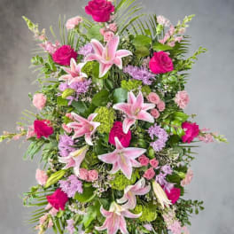 Tall pink and green standing spray with lilies and roses on a metal easel