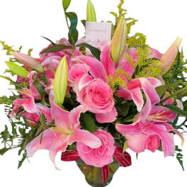Pink lilies and roses arranged in a glass vase