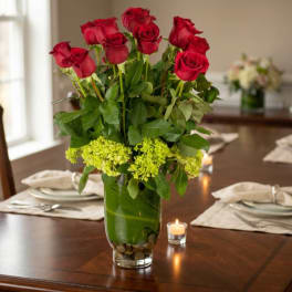Red roses in a clear glass vase on a dining table