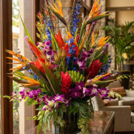 Tropical flower arrangement with purple orchids and bird-of-paradise in a glass vase