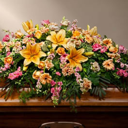Large floral casket spray with yellow lilies, roses, and pink accents