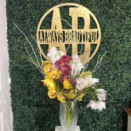 Tall vase arrangement of yellow, white, and purple orchids