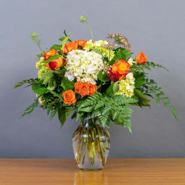Orange and white rose bouquet in a clear glass vase