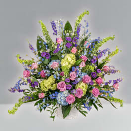 Large mixed bouquet of pink, purple, blue, and green flowers in a clear vase