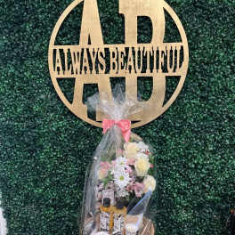 Gift basket with flowers, candles, and bath items wrapped in clear cellophane