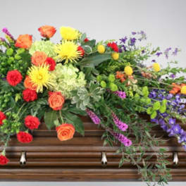 Colorful floral spray arranged on a wooden casket