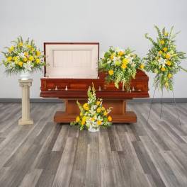 Set of yellow and white funeral floral arrangements around an open wooden casket