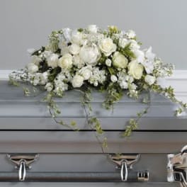White floral casket spray with trailing greenery