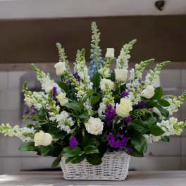 Tall basket arrangement of white roses and snapdragons with purple accents