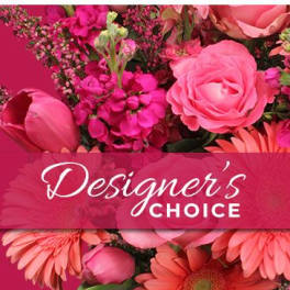Pink floral arrangement with roses and daisies behind a Designer's Choice banner