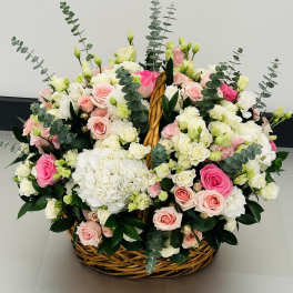 Basket arrangement of pink and white roses with hydrangeas and eucalyptus