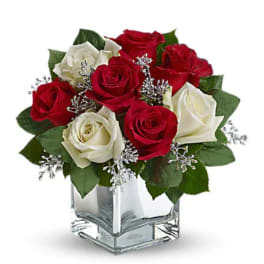 Red and white roses arranged in a clear square vase