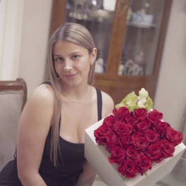 Woman holding a box of red roses with pale green orchids