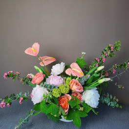 Mixed bouquet with pink anthuriums, roses, and white peonies in a low container
