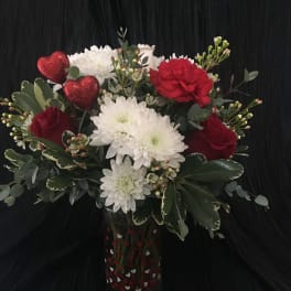 Bouquet of red and white flowers in a heart-decorated glass vase