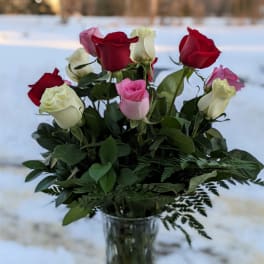 Bouquet of red, pink, and white roses in a clear glass vase