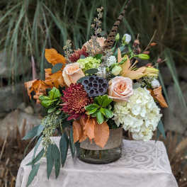 Autumn floral arrangement with roses, hydrangea, and chrysanthemums in a glass vase